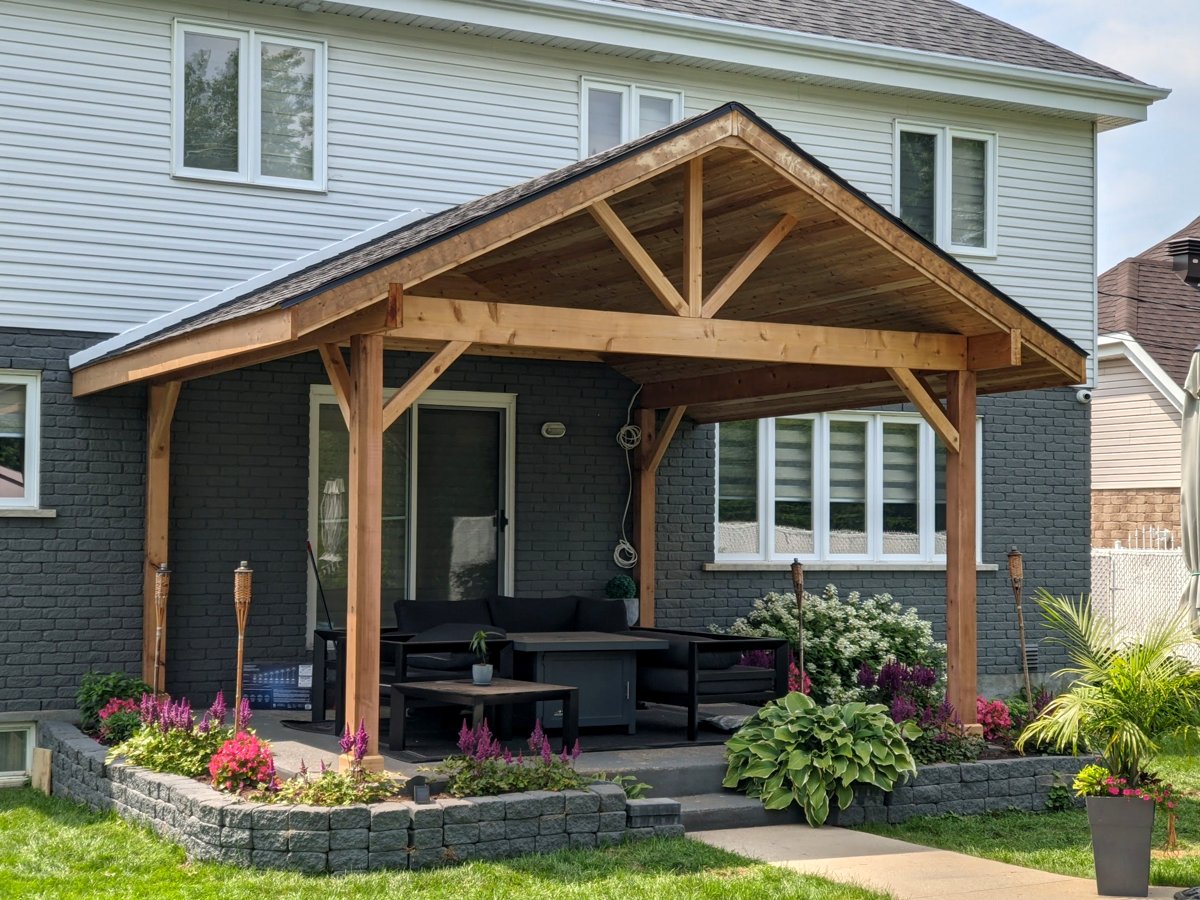 Pergola en cèdre à pignon au-dessus d’un patio arrière avec jardinières en pierre